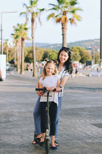 Happy family lifestyle. mother, boy, girl in city. ride scooters. laughing on a summer. fun