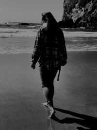 Rear view of woman walking on shore at beach