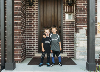 Portrait of boys standing against door