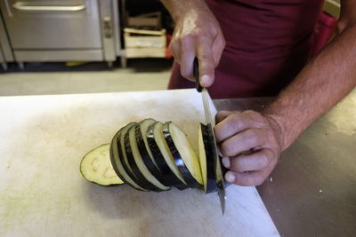 Midsection of man slicing eggplant on kitchen counter