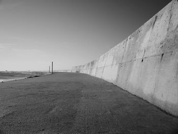 Footpath by wall against clear sky