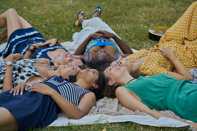 Group of smiling female friends laying on a towel in a park having fun