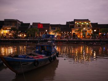 Boats moored on illuminated city at night