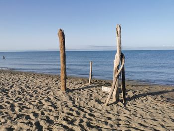 Wooden posts on beach against clear sky