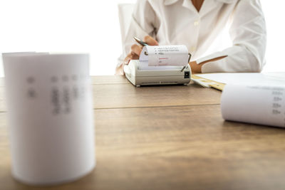 Midsection of woman holding paper with text on table