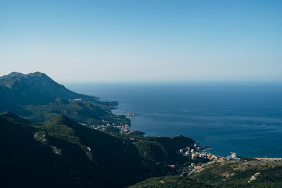 Scenic view of sea and mountains against clear blue sky