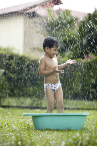 Happy boy standing in bathtub on grass at back yard