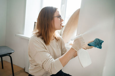 Positive woman cleaning glass at home