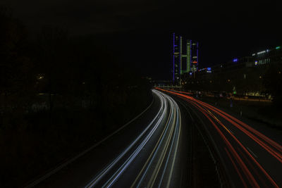 Light trails on road amidst illuminated buildings in city at night