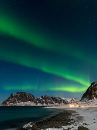 Scenic view of illuminated snowcapped mountains against sky at night