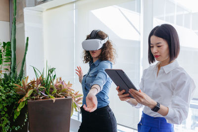 Two standing women in the office working with vr helmet and tablet