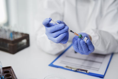 Midsection of doctor holding vaccine