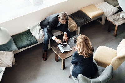 Mature businessman discussing over digital tablet with female colleague in cafe