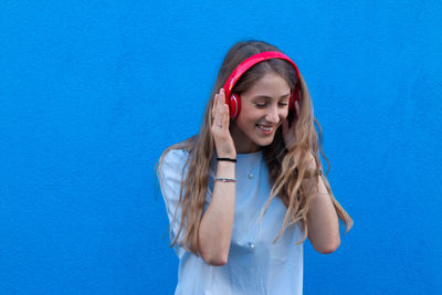 Portrait of a smiling young woman against blue wall