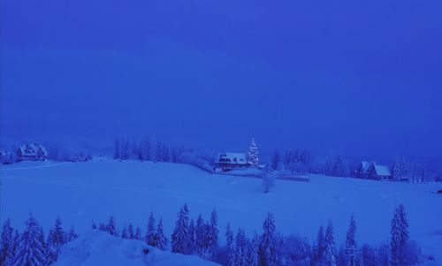 Snow covered land and trees against blue sky