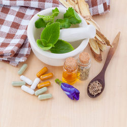 High angle view of herbs in spices with capsules on table