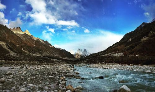 Scenic view of river by mountains against sky