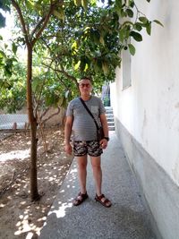 Full length portrait of young man standing against trees