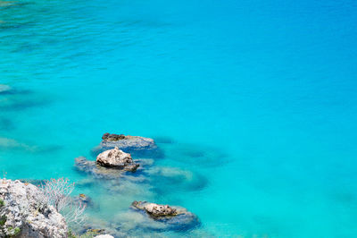 High angle view of rocks by sea against blue sky