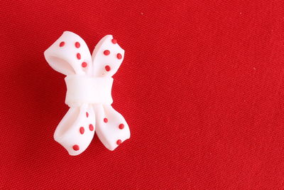 Directly above shot of white bow on red textile