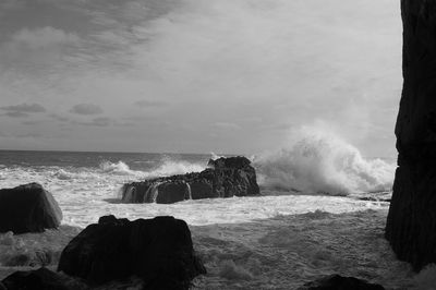 Waves splashing on shore against sky