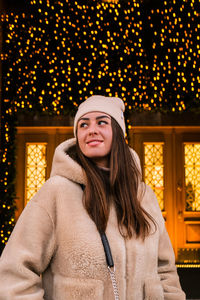 Young woman looking away while standing against christmas decoration