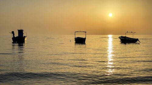 Silhouette sailboats in sea against sky during sunset