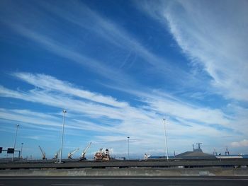 Cars on road against cloudy sky