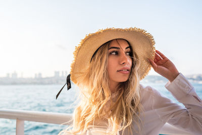 Close-up of beautiful young woman wearing sun hat against clear sky