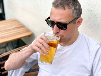 Middle aged man is drinking beer in a cafe or restaurant pub outdoor. drinking alcohol. candid