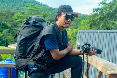 Young photographer standing holding digital camera on mountain forest resort active living concept