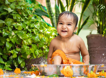 Cute toddler baby boy bathing in decorated bathtub at outdoor from unique perspective