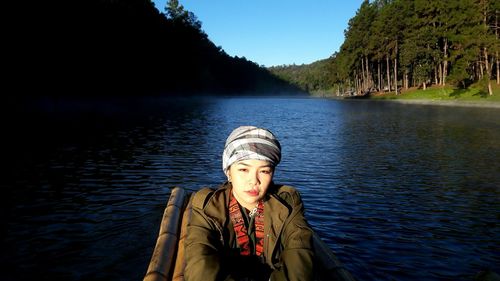 Portrait of man standing by lake against sky