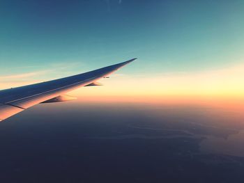 Airplane flying in sky at sunset