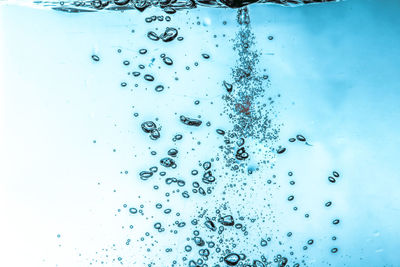 Close-up of water drops on glass against blue background