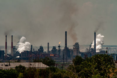 Smoke emitting from factory against sky