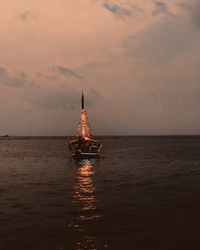 Sailboat sailing on sea against sky during sunset