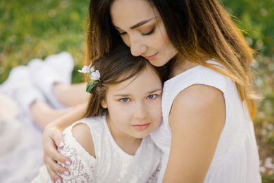 A happy young woman sits on a picnic blanket and hugs her daughter. mother and daughter's picnic