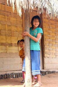 Full length of a smiling young woman standing against brick wall