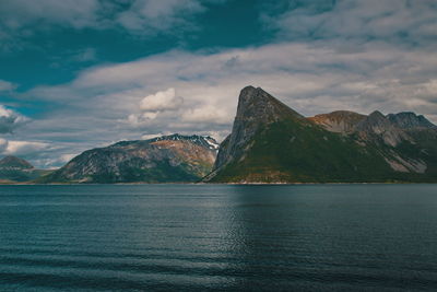 Scenic view of sea by mountains against sky