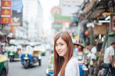 Portrait of young woman standing in city