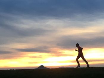 Silhouette man standing on land against sky during sunset