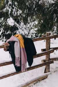Coat and scarf hanging over a wooden fence