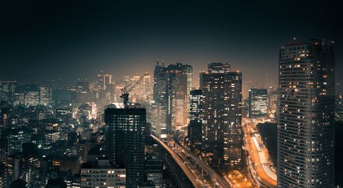 Illuminated buildings in city against sky at night