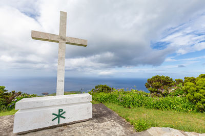 Cross sign on grass against sky