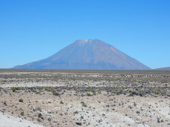 Scenic view of arid landscape against clear blue sky