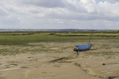 Boat moored on beach against sky