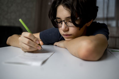 Boy writing with pen on paper at home