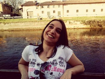Portrait of smiling young woman against canal