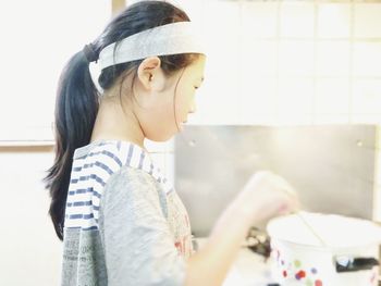 Side view of girl preparing food in kitchen